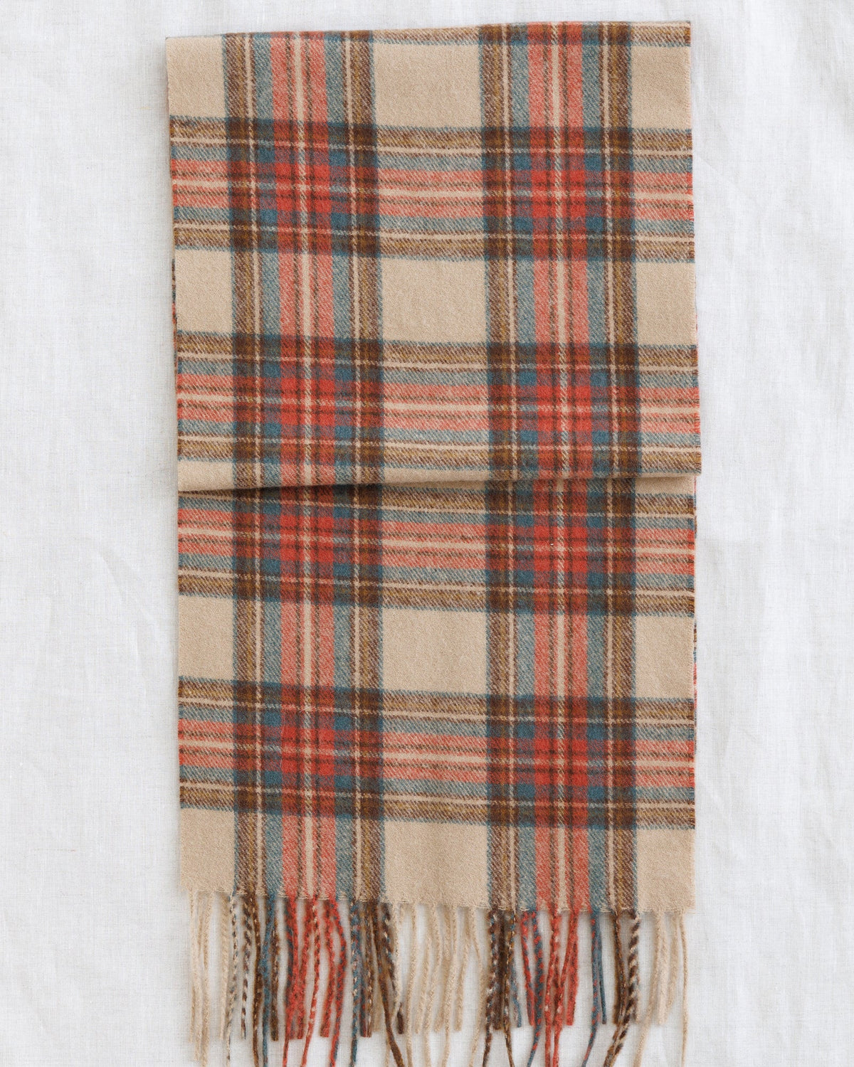Downeast Golden Hour scarf with vibrant, warm-toned fabric displayed flat with fringed edges.