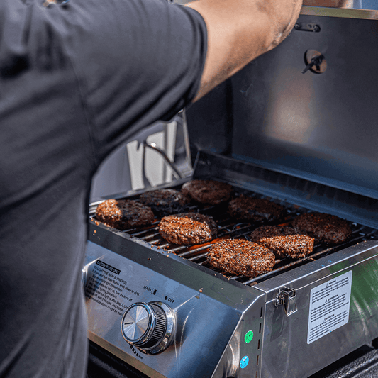 Stainless Monument Grills tabletop propane gas grill with cooking surface and control knobs, ideal for outdoor grilling.