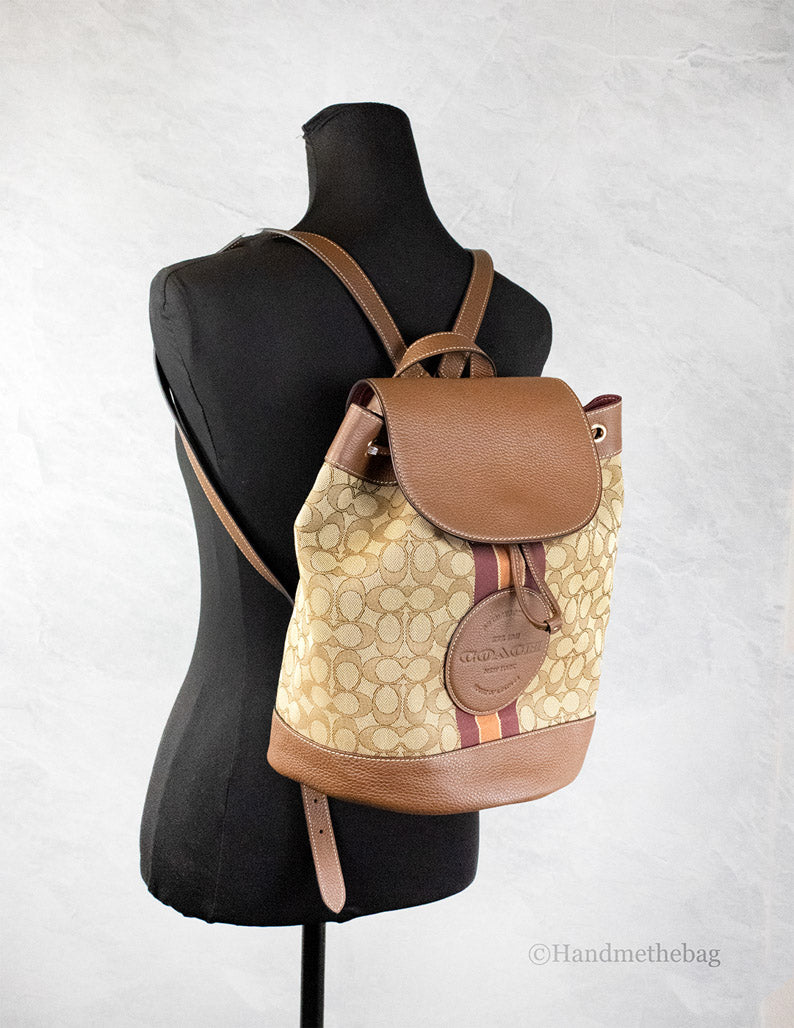 Coach Dempsey khaki saddle signature jacquard canvas patch backpack with adjustable straps and multiple compartments.