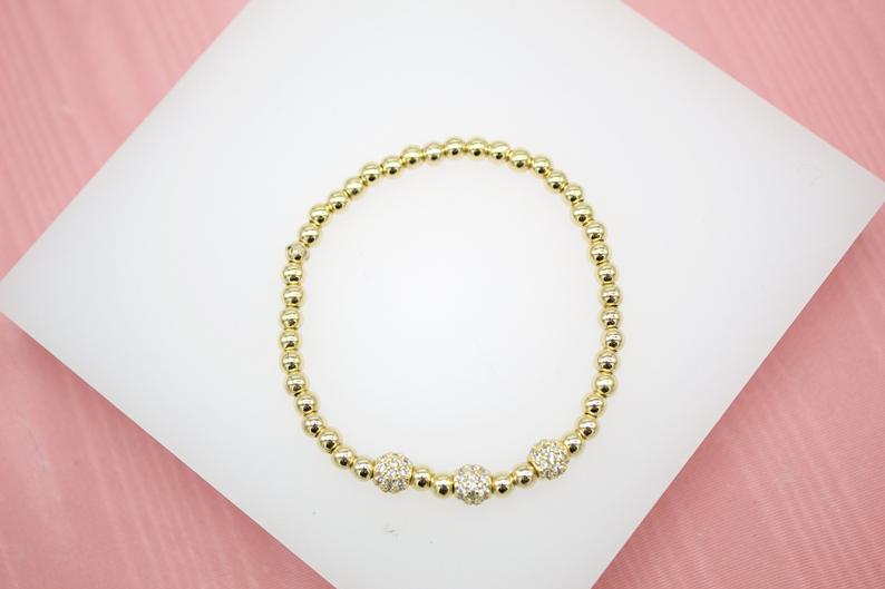 18K gold filled elastic bead bracelet by MIA Jewelry featuring 4mm gold beads and three round CZ charm accents.