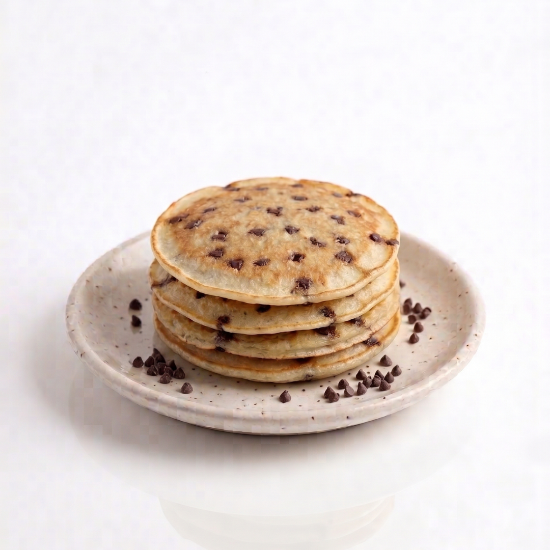 Plate of AmBari Nutrition chocolate chip pancakes topped with syrup, showcasing fluffy pancakes with chocolate chips.
