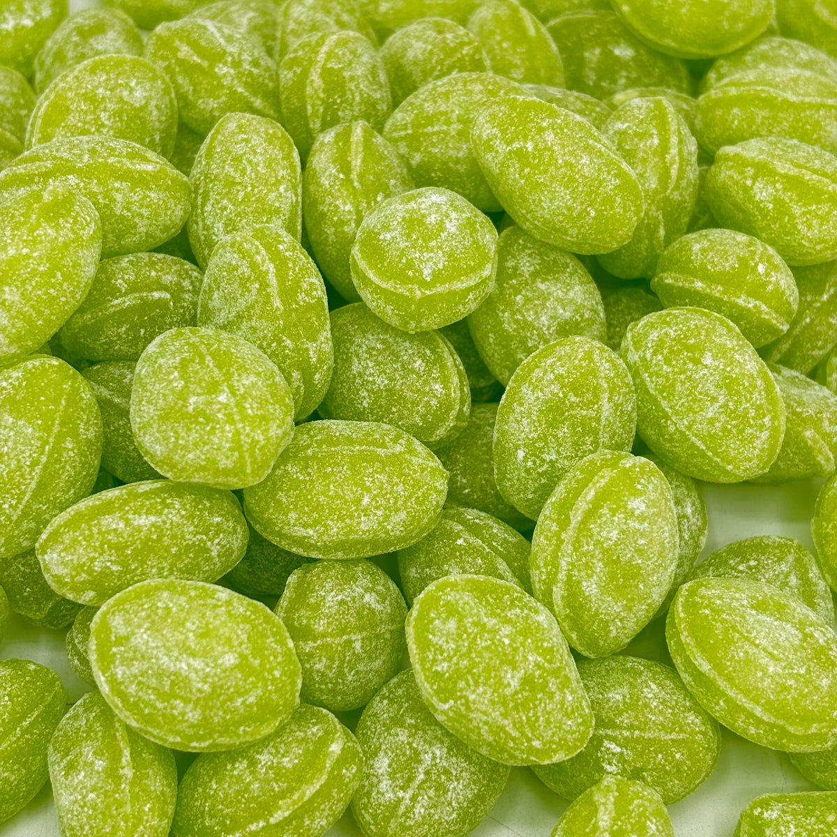Green apple flavored Claeys hard candy drops from Candy In Bulk in a large bulk value bag, showcasing vibrant green candies.