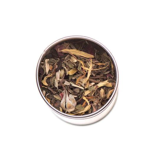 Ayurvedic tea in a glass mug featuring Cool & Calm Blend by Paavani Ayurveda for Pitta balance, with herbs and tea leaves visible.