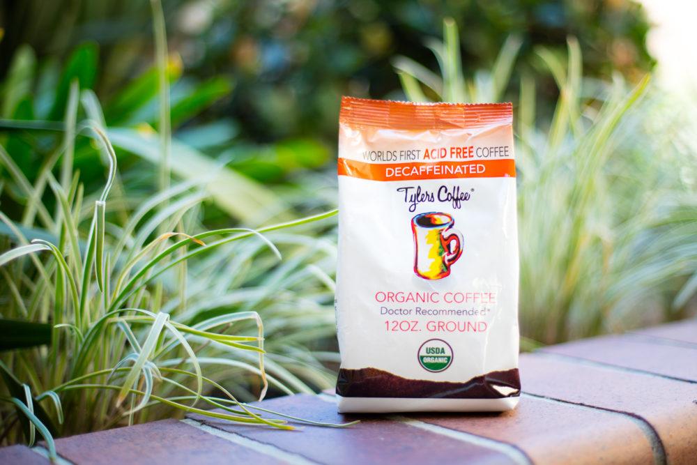 Decaf acid-free ground coffee in a 12oz bag by Tylers Coffees, showing the packaging with coffee grounds inside.