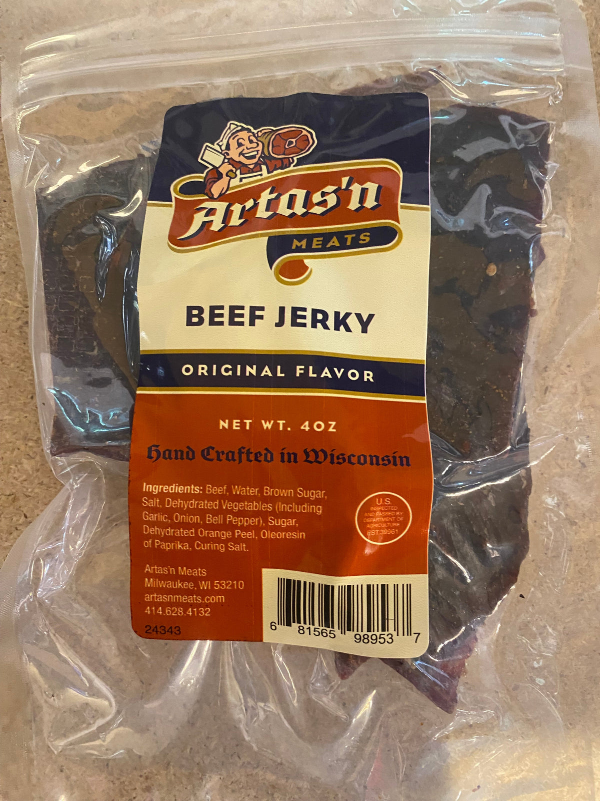 Slices of savory Artas'n Meats Original Beef Jerky with visible spices and a textured surface on a wooden background.