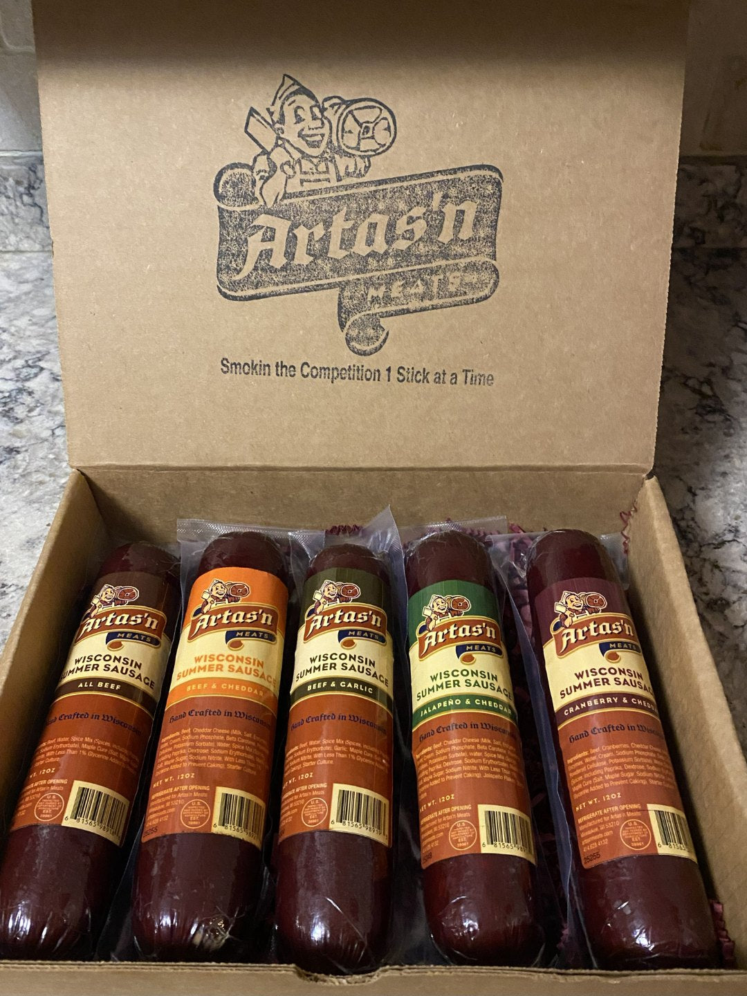 Artas'n Meats Smoke House Five gift box with five assorted sausages on a wooden surface