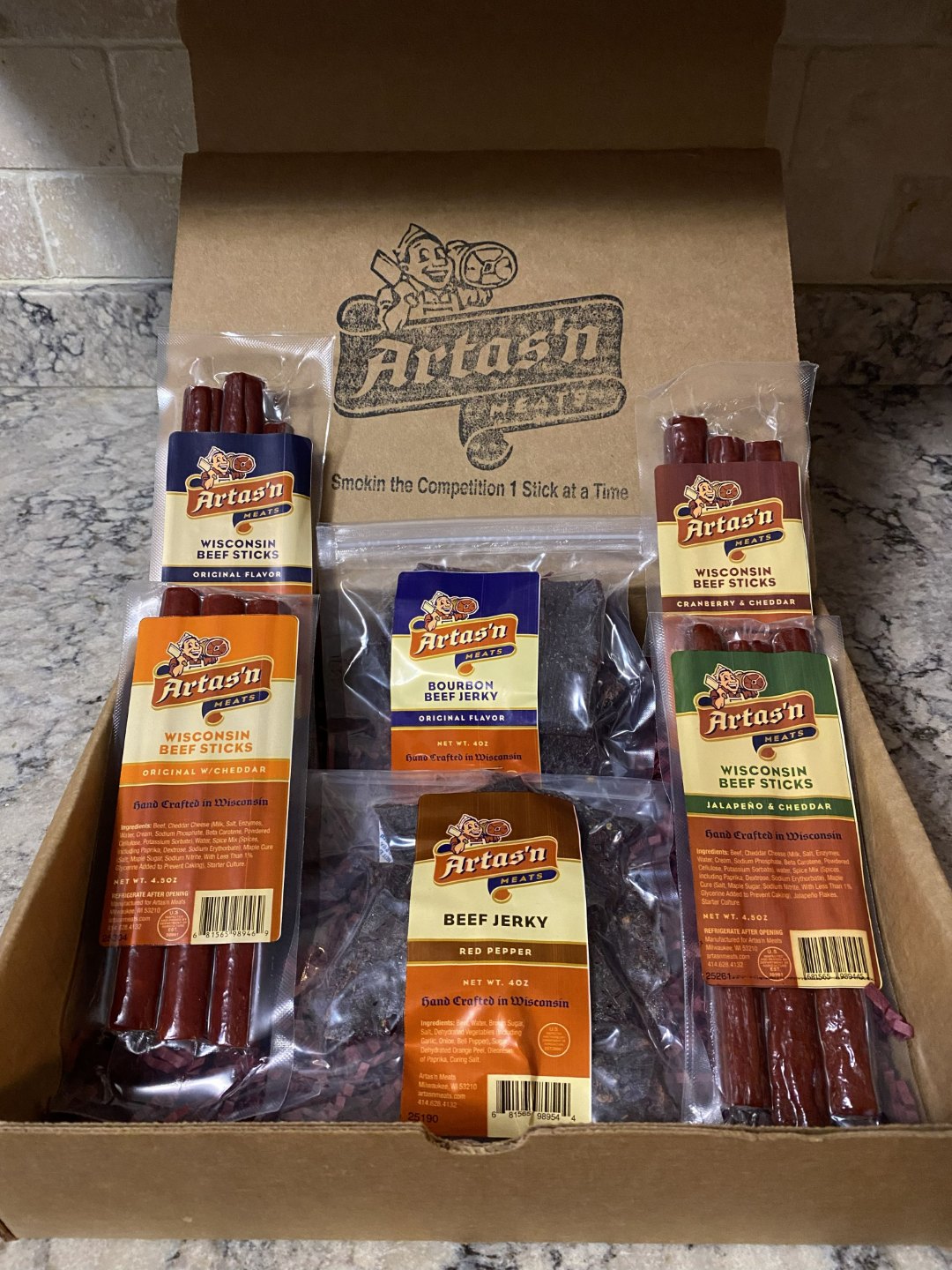 Artas'n Meats Beef Stick and Jerky Sampler Pack in a gift box, featuring assorted beef jerky and stick varieties.