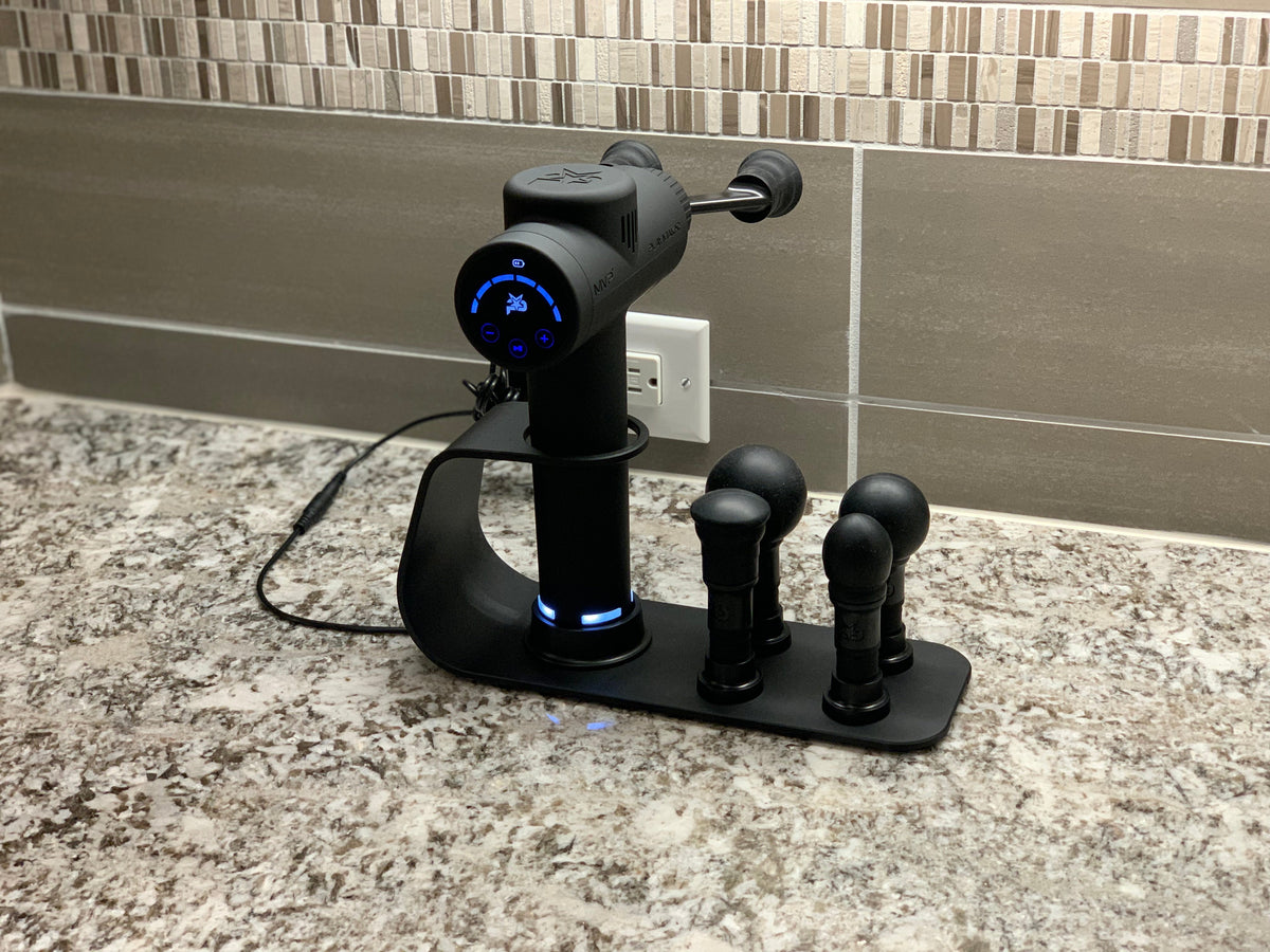 iReliev MVP+ PowerUp charging station for percussion massager accessories, shown with connected attachments and charging ports.