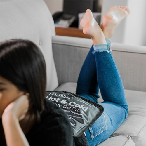 iReliev premium reusable hot and cold therapy gel pack with securement straps, shown in a lifestyle setting for pain relief.