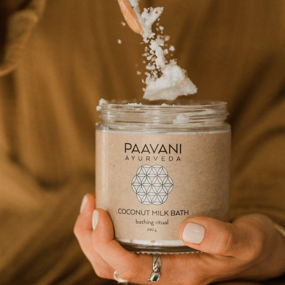 A simple image of a coconut milk bath product by Paavani Ayurveda Skincare, featuring a bottle with natural, herbal ingredients for skin and spirit.
