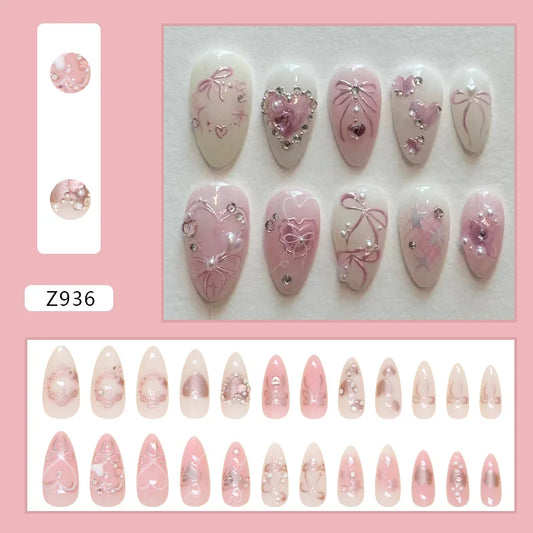 Set of 24 pink almond false nail tips by Blushimmer featuring bowknots, love hearts, and pearl accents for Korean press-on nails.