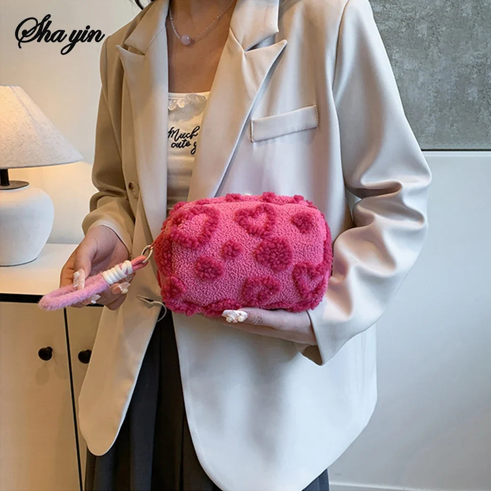Soft blush pink plush makeup bag with handle, featuring a love print, perfect for travel cosmetic storage and organization.