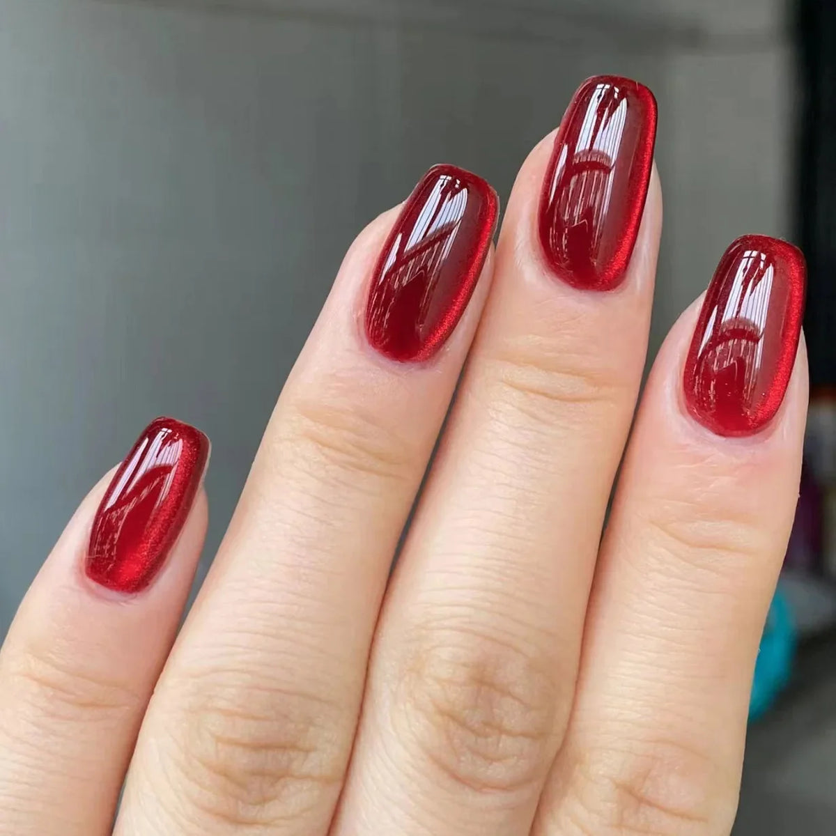 Set of 24 glossy red cat's eye press-on nails by Blushimmer with nude almond shape, full cover, and removable charms.