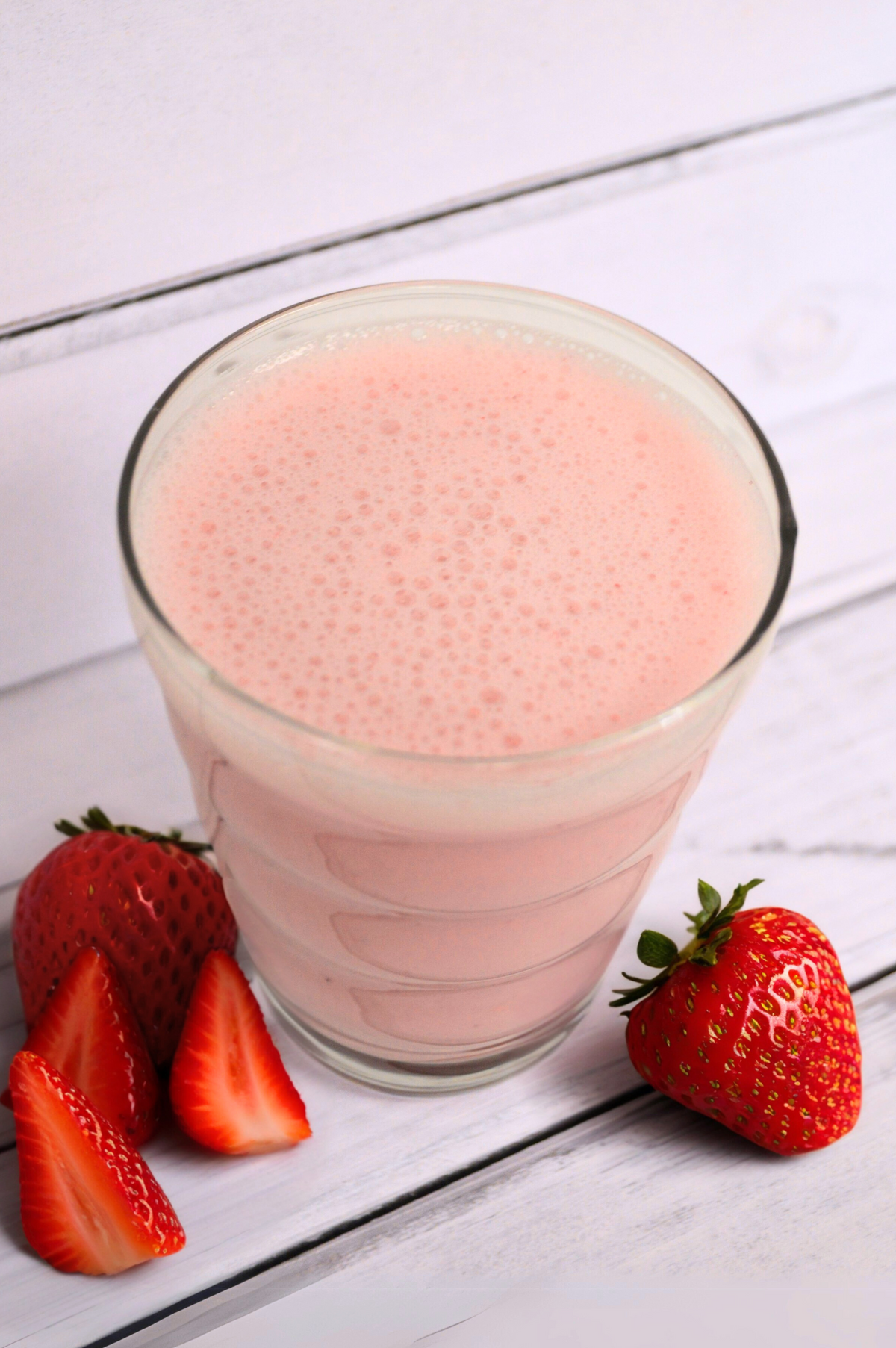 AmBari Nutrition Strawberry Blast smoothie shake in a clear glass with fresh strawberries and a creamy pink appearance.
