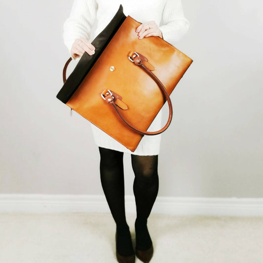 Tan leather laptop bag with a flap and handles, designed by Good Hides, showcasing a spacious and stylish 17-inch bag for laptops.