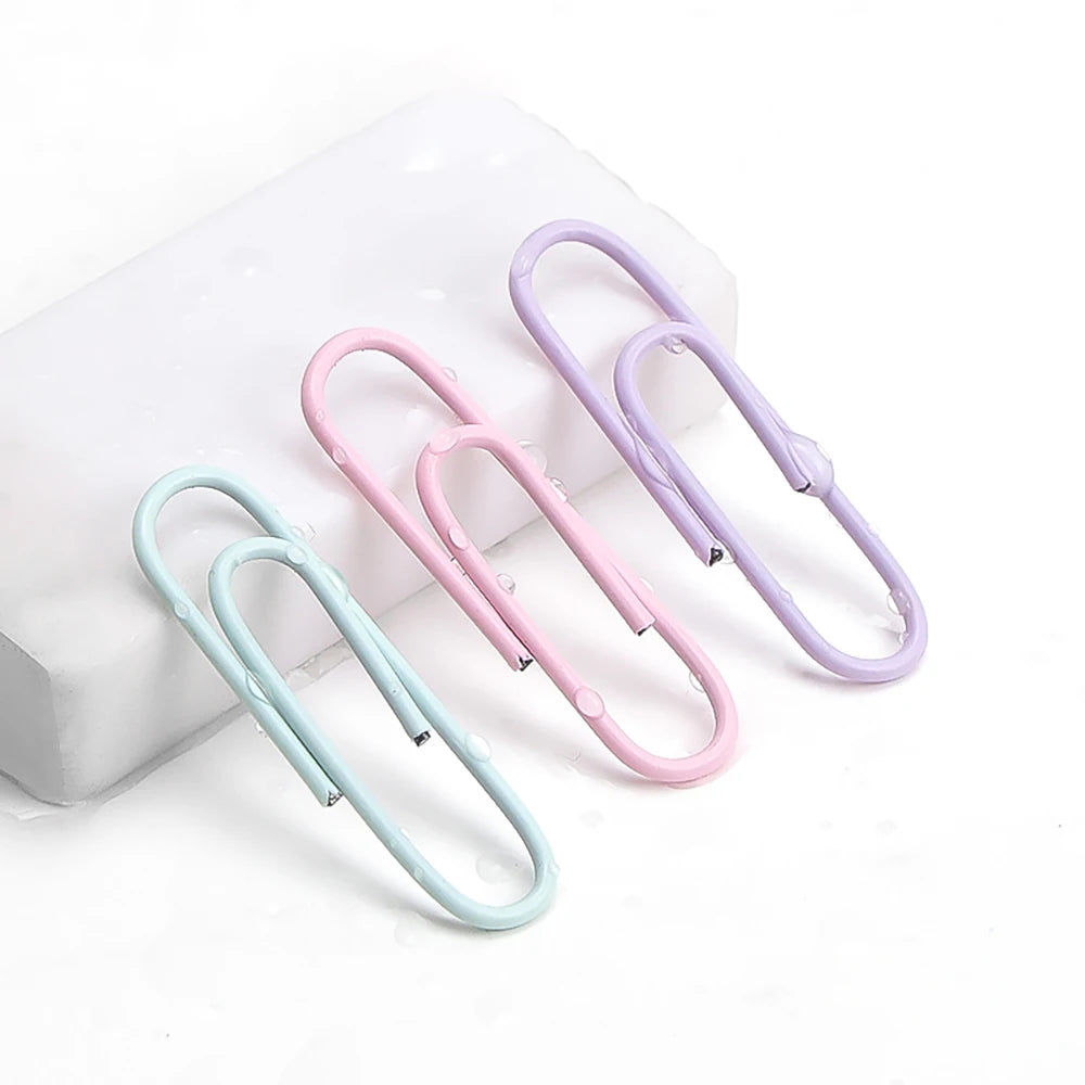 Assorted color paper clips and large file bookmarks in a storage box, ideal for office supplies and stationery organization.