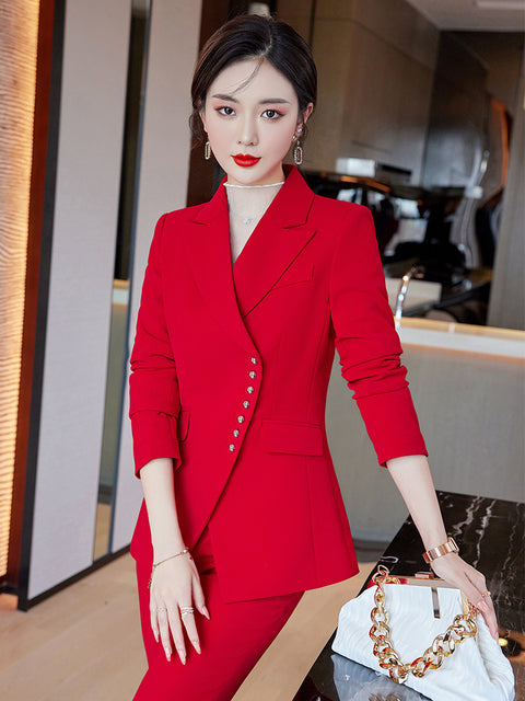 Red two-piece women's business suit with pants, stylish and professional, featuring a tailored blazer and matching trousers.