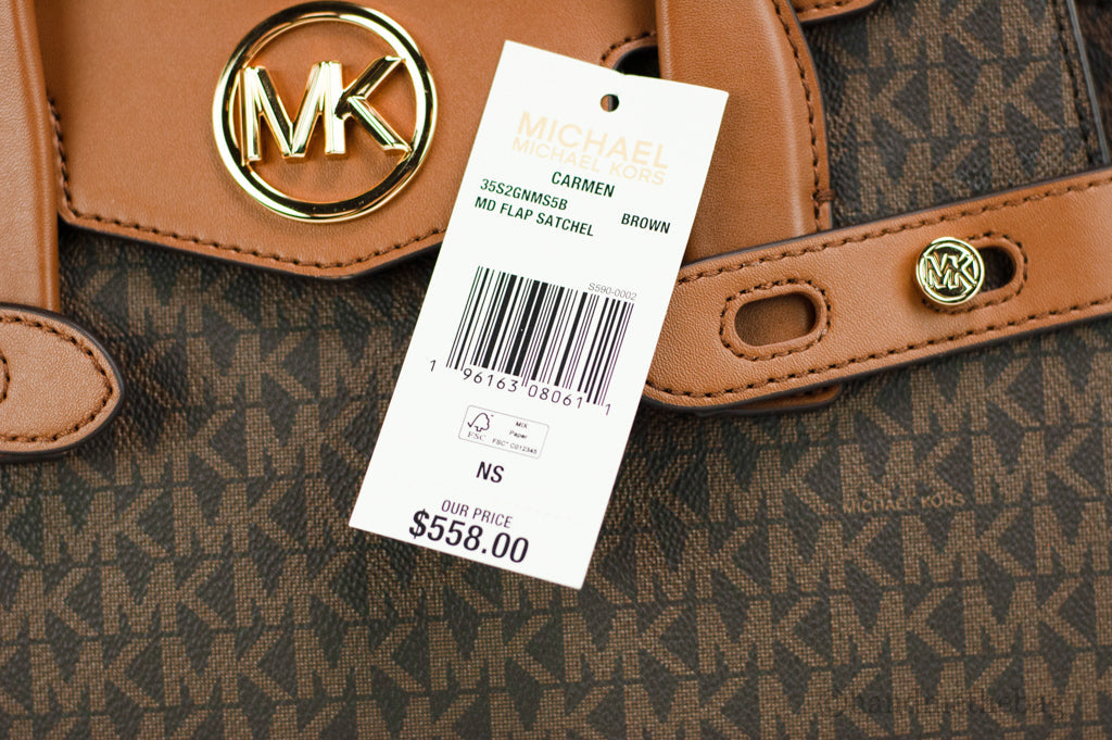 Brown Michael Kors Carmen Signature satchel with structured design, top handles, and gold-tone hardware on a neutral background.