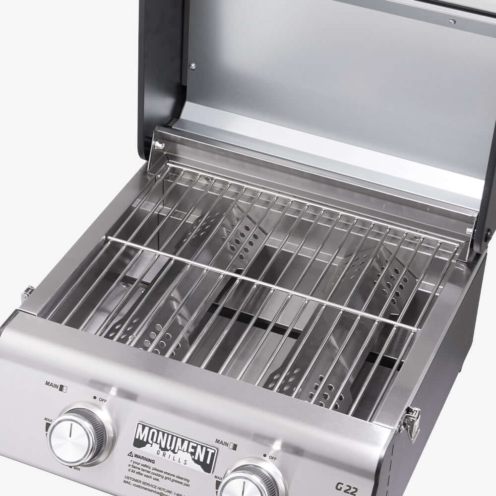 Stainless G22 tabletop propane gas grill by Monument Grills with cooking grates and control knobs on a compact outdoor table.