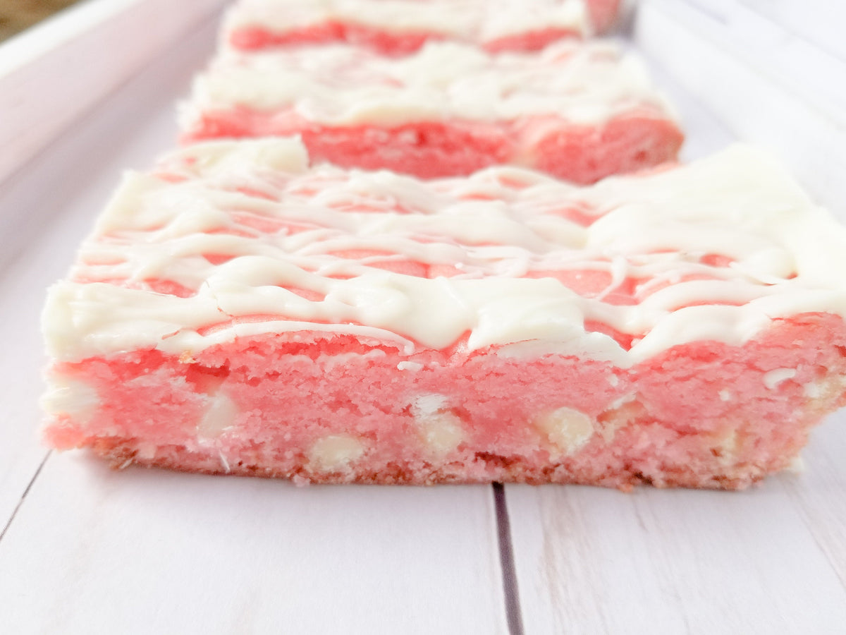 Strawberry Blondies from Let's Get Baked Artisan Desserts, featuring golden cake bars with visible strawberry pieces and a glossy finish
