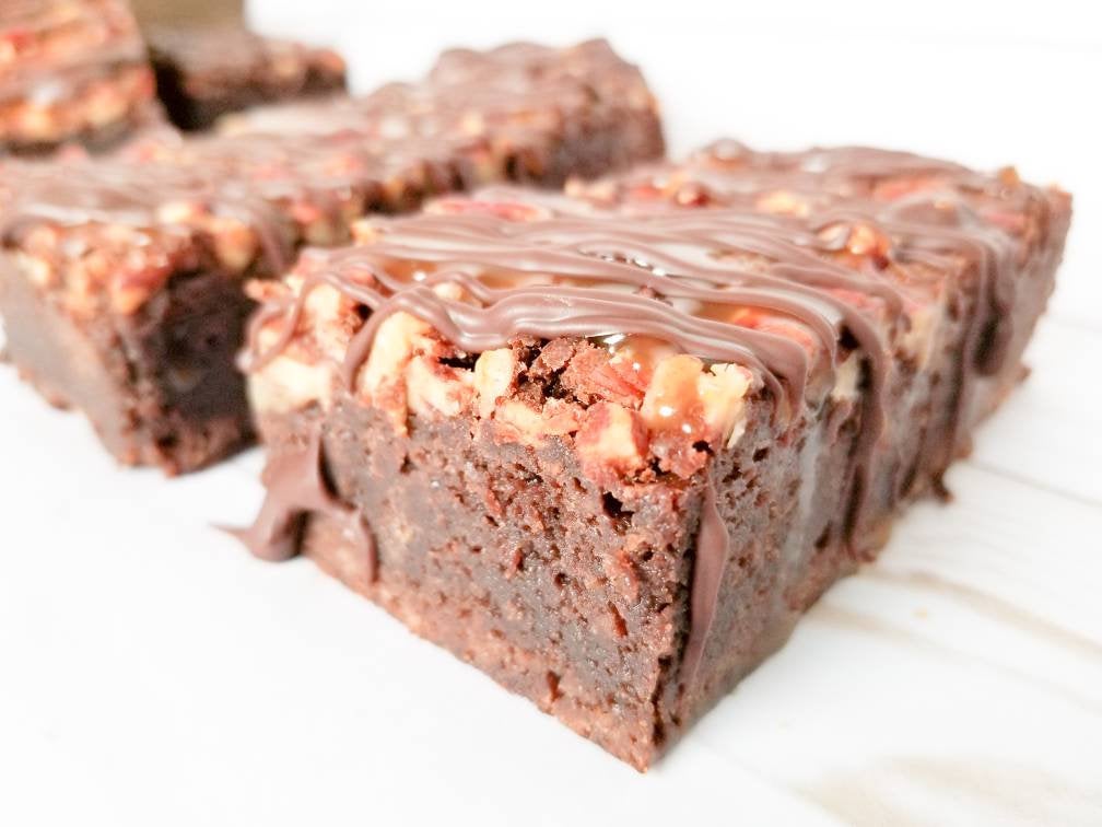 Turtle brownies from Let's Get Baked Artisan Desserts featuring rich chocolate, caramel, pecans, and a glossy topping.