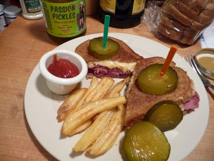 Reuben sandwich with Passion Pickles® Ghost Pepper Homestyle Chips on a plate, showcasing spicy pickle slices and crispy bread.