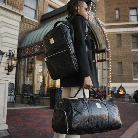 Black monogram leather duffle bag by Sole Premise, featuring sturdy handles and spacious interior for travel and daily use.