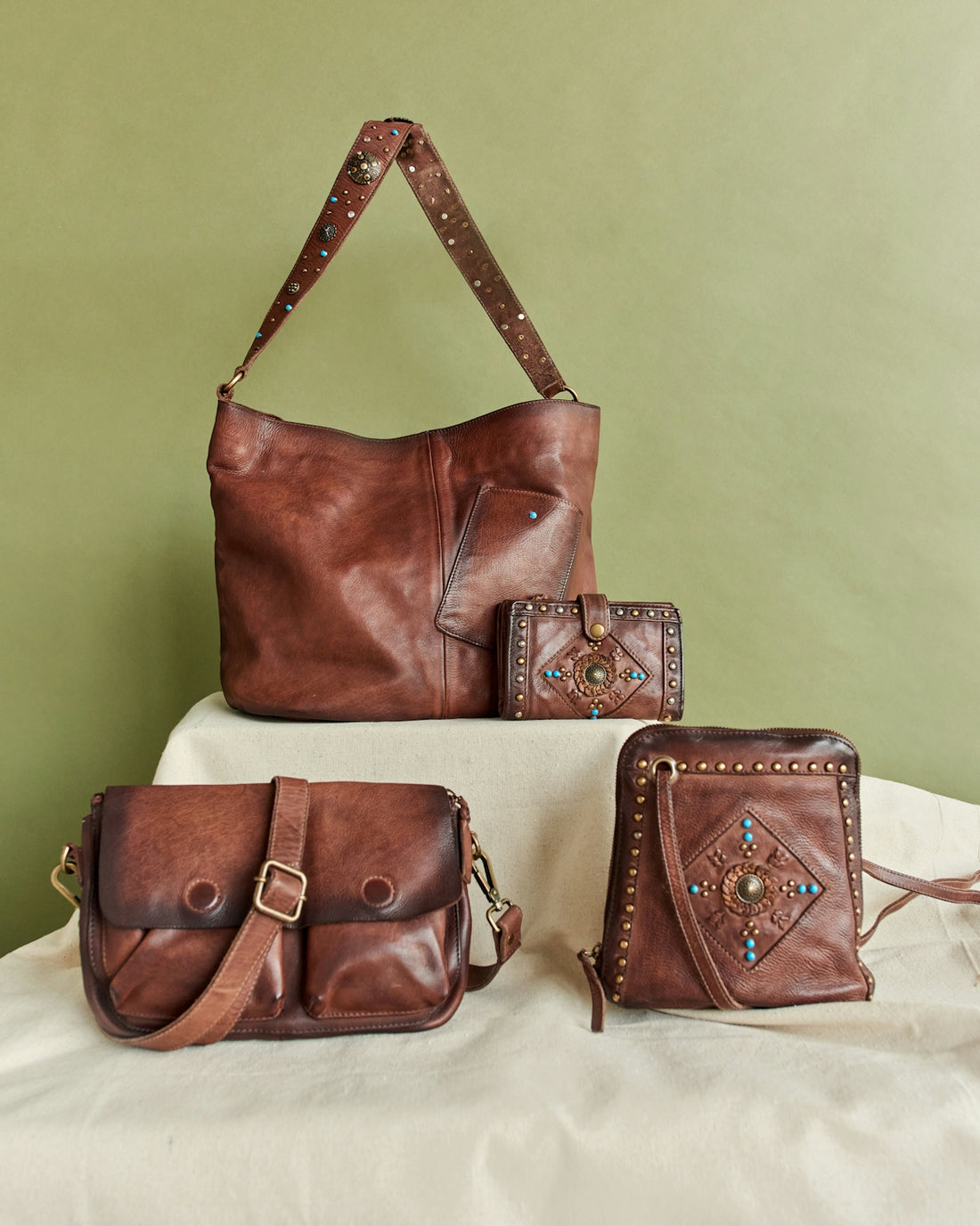Four brown leather bags and wallets arranged artfully