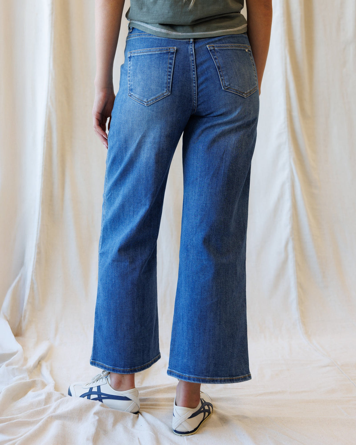 Dark blue Downeast high rise seamed wide leg ankle denim jeans displayed on a hanger.
