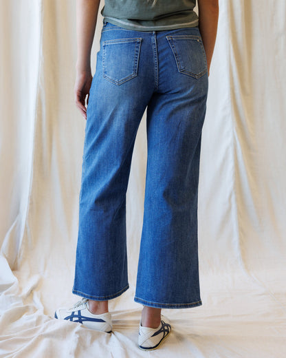 Dark blue Downeast high rise seamed wide leg ankle denim jeans displayed on a hanger.