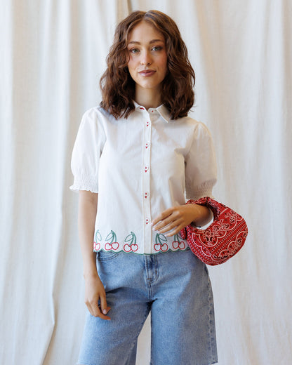 Cherry cute button-down top by Downeast, featuring a colorful cherry print and classic collar, displayed on a hanger.