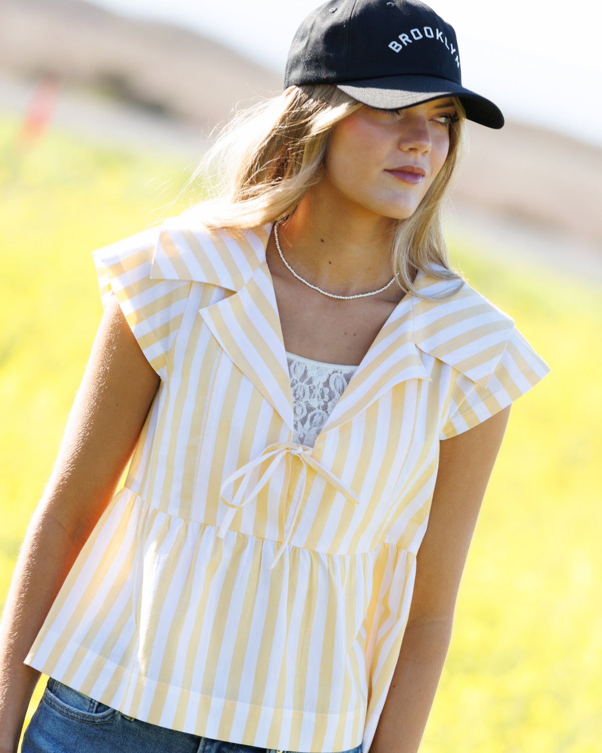Downeast Sunshine Stripe Top, a casual women's blouse with bright yellow and white stripes, displayed on a hanger.