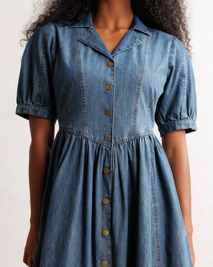 Downeast Orchard Denim Dress displayed on a hanger, featuring a casual sleeveless design with side pockets and a button-front style.