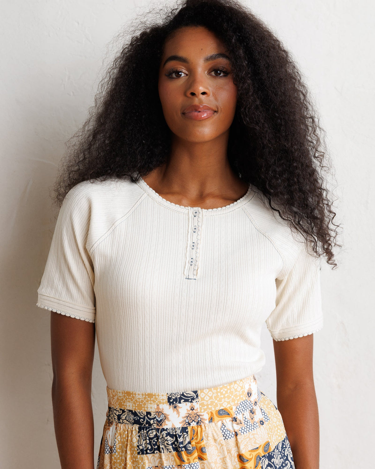 Downeast Pointelle Pretty Top, a stylish women's blouse with delicate knit patterns and short sleeves, displayed on a hanger.
