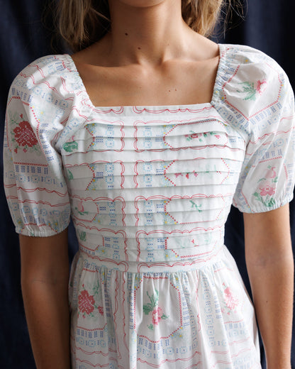 Downeast cross stitch crochet dress displayed on a hanger, showcasing intricate pattern and lightweight fabric for elegant summer style.
