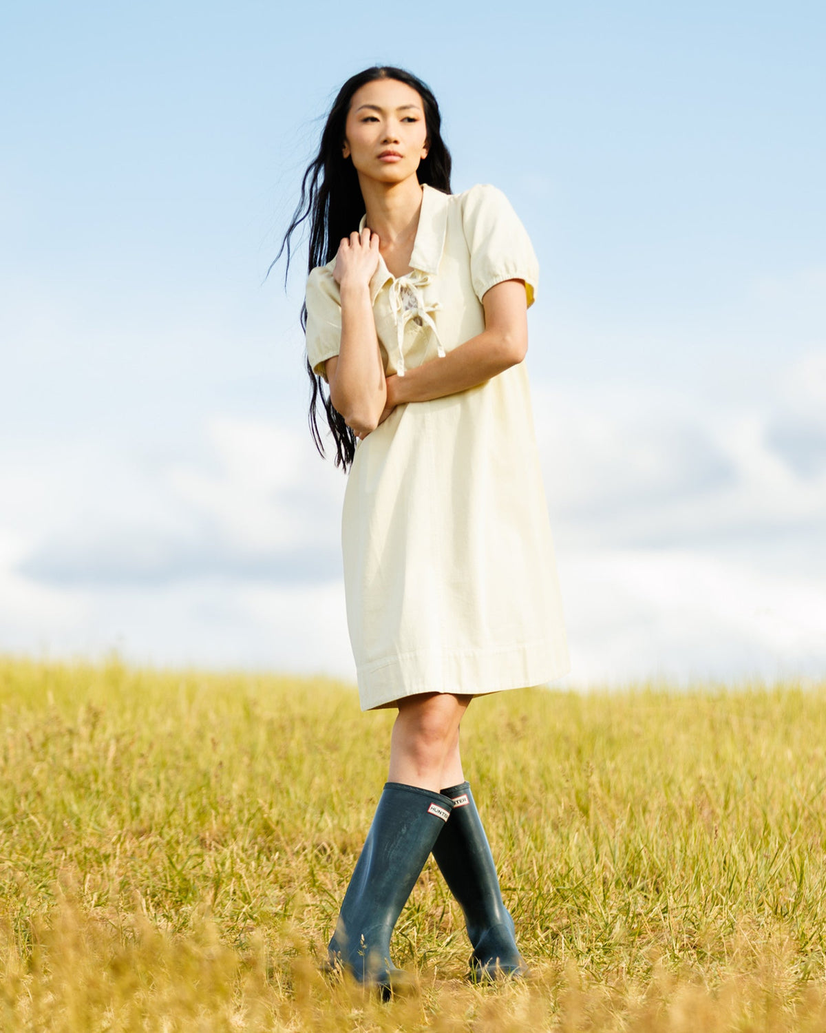 Downeast Demure Denim Dress hanging on a wooden hanger, showcasing its classic blue denim fabric and simple design.