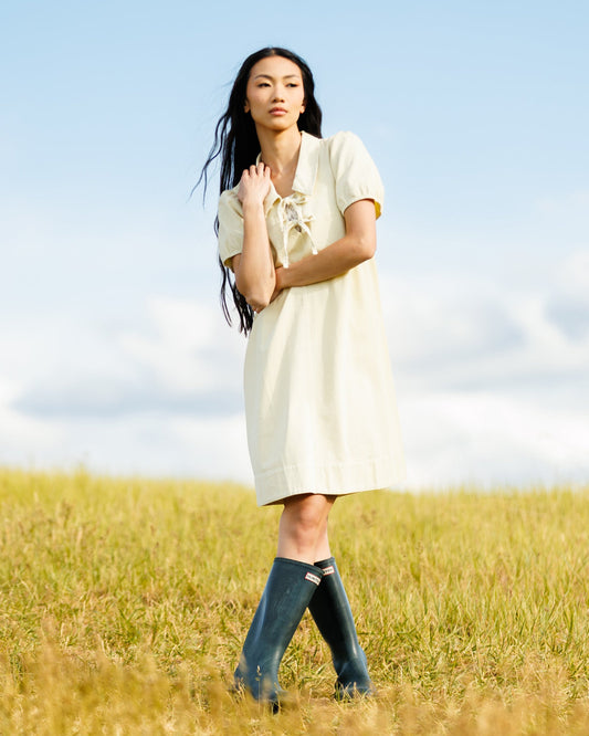 Downeast Demure Denim Dress hanging on a wooden hanger, showcasing its classic blue denim fabric and simple design.