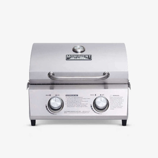 Stainless Monument Grills tabletop propane gas grill with cooking grate and control knobs for outdoor grilling.
