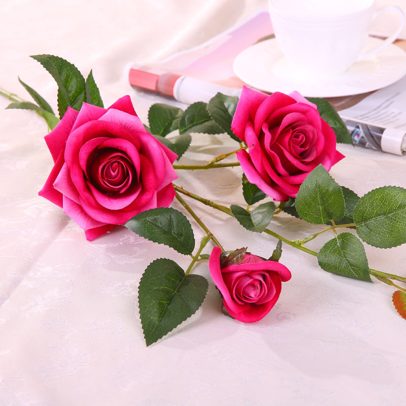 Artificial rose flower in bloom with realistic petals and green leaves