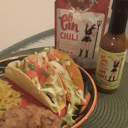Bottle of Cinderosa Ranch Cin Chili Serrano Hot Sauce showing the label and vibrant orange-red sauce inside the clear glass bottle.