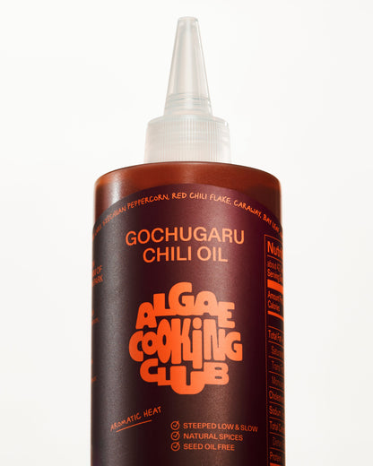 Algae Cooking Club Chef Squeeze Trio oil bottles with colorful labels, arranged on a wooden surface.