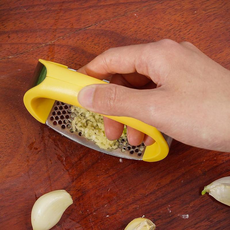 Stainless steel manual garlic press and masher with curved design for kitchen use