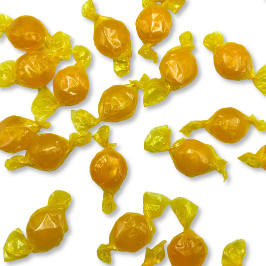 Two butterscotch buttons hard candies from Candy In Bulk in a clear plastic bag, showcasing their round shape and golden color.