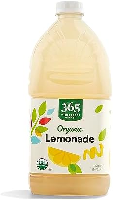 Bottle of 365 by Whole Foods Market Organic Lemonade, 64 Fl Oz, with fresh lemon slices and vibrant yellow label on a clear glass bottle.