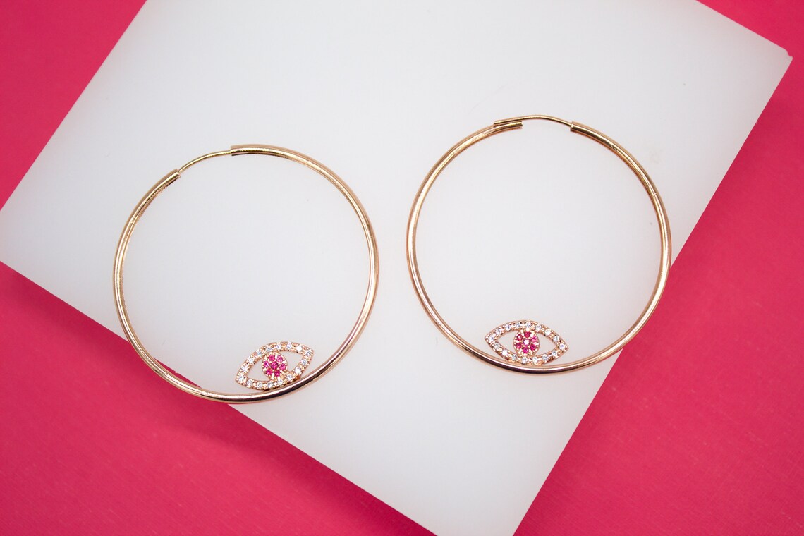 Evil eye endless hoop earrings by MIA Jewelry with micro CZ stones, featuring a silver-tone hoop design.