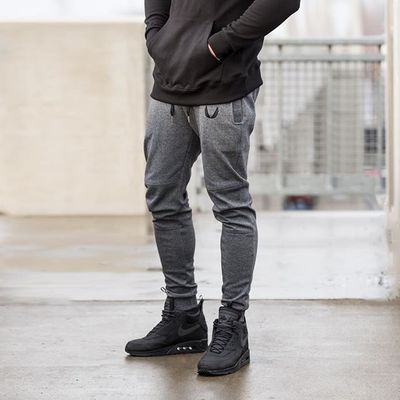Black running training pants with elastic waistband and tapered fit; front view reclining on a model