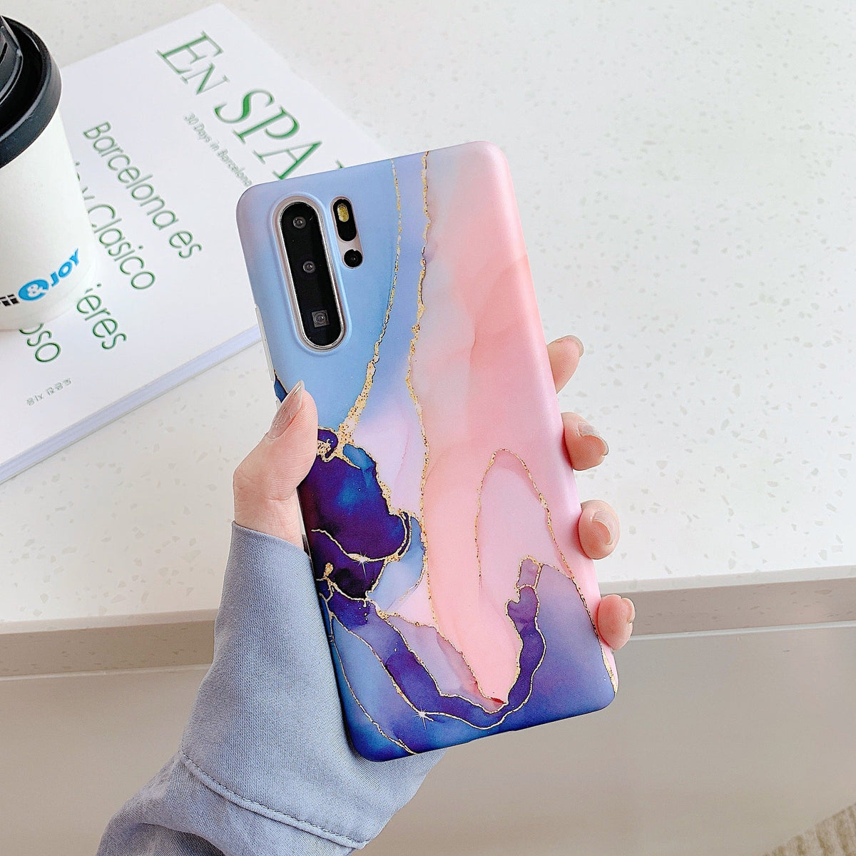 Marble phone case with white and gray stone pattern encasing a smartphone