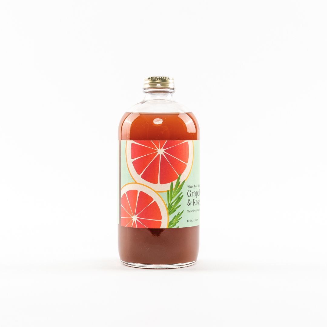 Wood Stove Kitchen grapefruit and rosemary cocktail and mocktail mixer bottle, 16 fl oz, with fresh grapefruit and rosemary herbs visible.