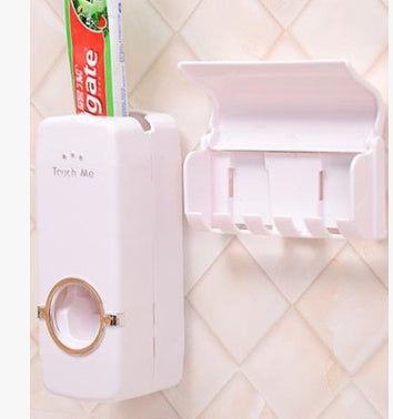 Automatic toothpaste squeezer dispenser mounted on a bathroom wall, white plastic design with toothpaste tube inserted