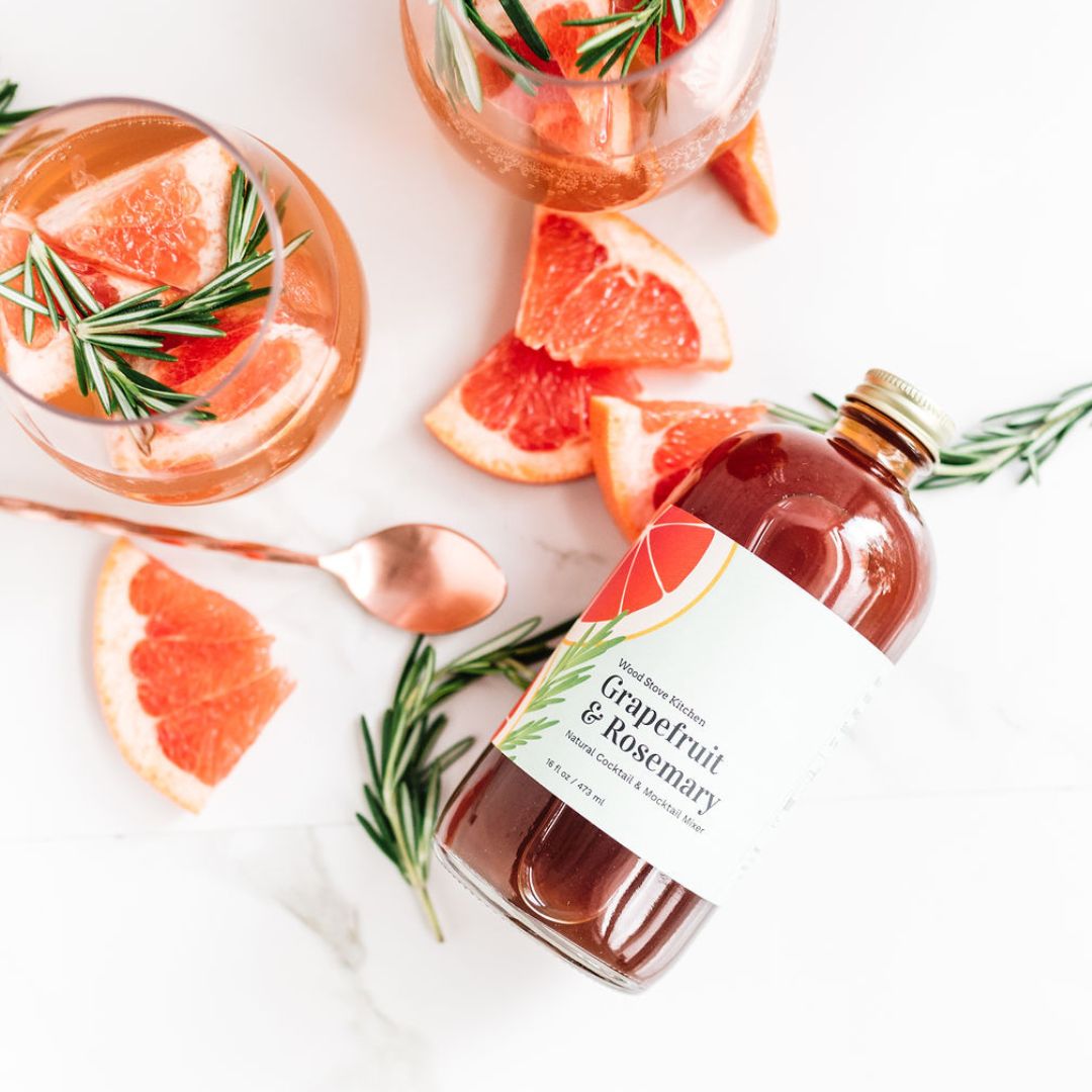 Grapefruit and rosemary cocktail mixer by Wood Stove Kitchen in a 16 fl oz bottle, showcasing fresh ingredients and vibrant color.